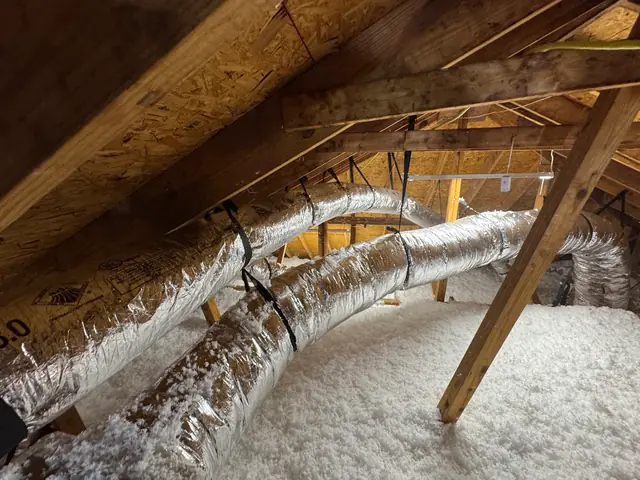 Insulated flex duct runs above blown insulation in a Texas attic
