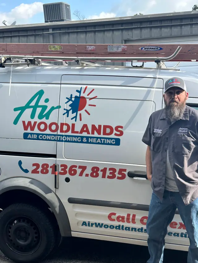 An Air Woodlands service van in full livery with a technician standing beside it