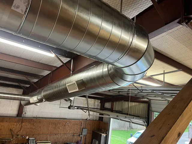 A large spiral duct trunk run installed in a commercial steel building